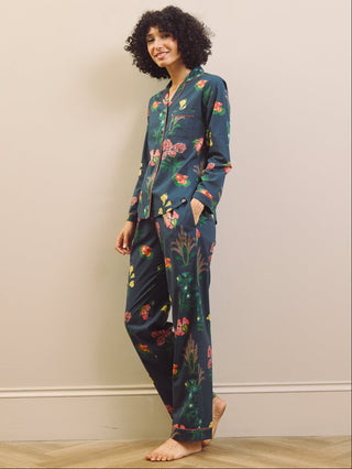 Woman wearing a navy blue floral pyjama set against a plain background