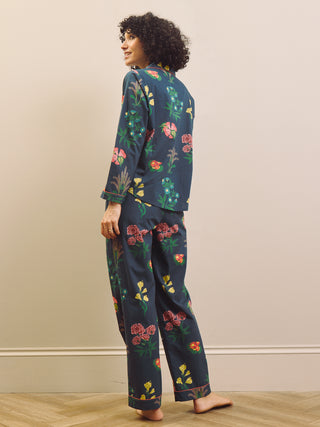 Woman wearing a navy blue floral pyjama set against a plain background