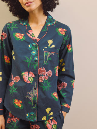 Woman wearing a navy blue floral pyjama set against a plain background