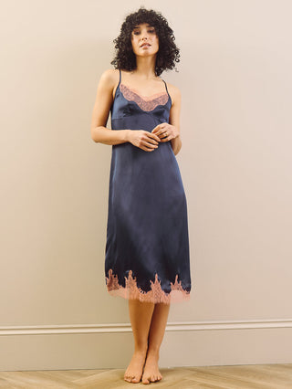 Model Wears Navy blue night dress with pink lace trim against a plain wall. 