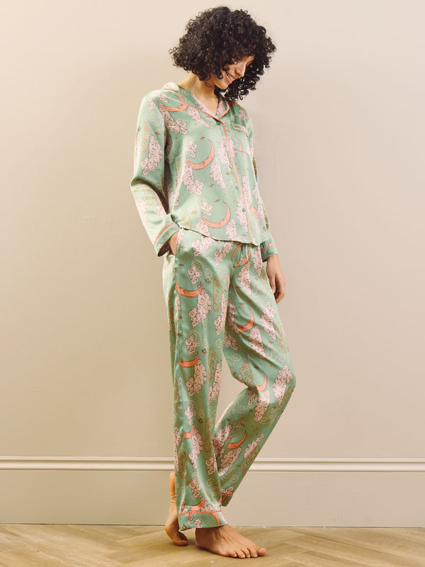 Model wearing a green moon and clouds design long satin pyjama set against a beige background