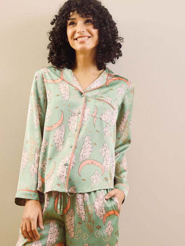 Model wearing a green moon and clouds design long satin pyjama set against a beige background
