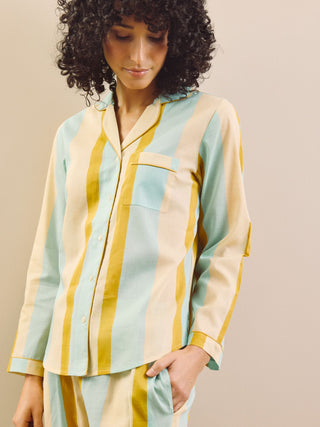 Woman wearing a striped pajama set against a beige wall.