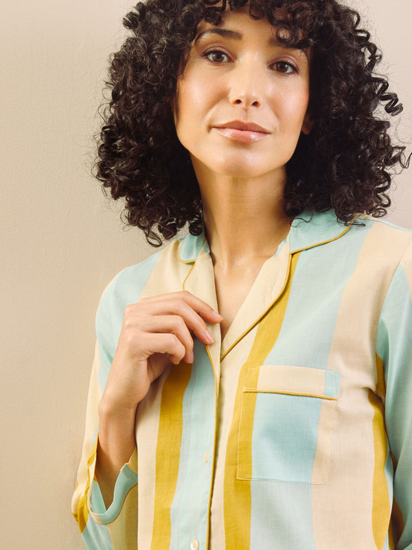 Woman wearing a striped pajama set against a beige wall.