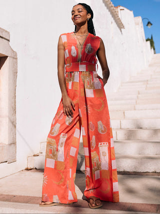 A woman standing in a terracotta-colored cotton voile jumpsuit with a geometric Moroccan fruit print, designed with a modern silhouette.