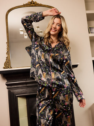 Woman wearing a satin halloween pyjama set playfully in front of a mirror.