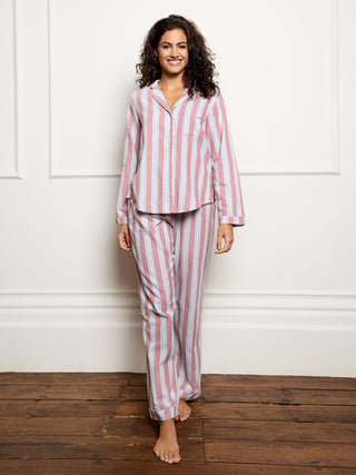 Woman wearing a red and white striped pajama set against a white wall.