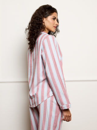 Woman wearing a pink and white striped pyjama set against a white background