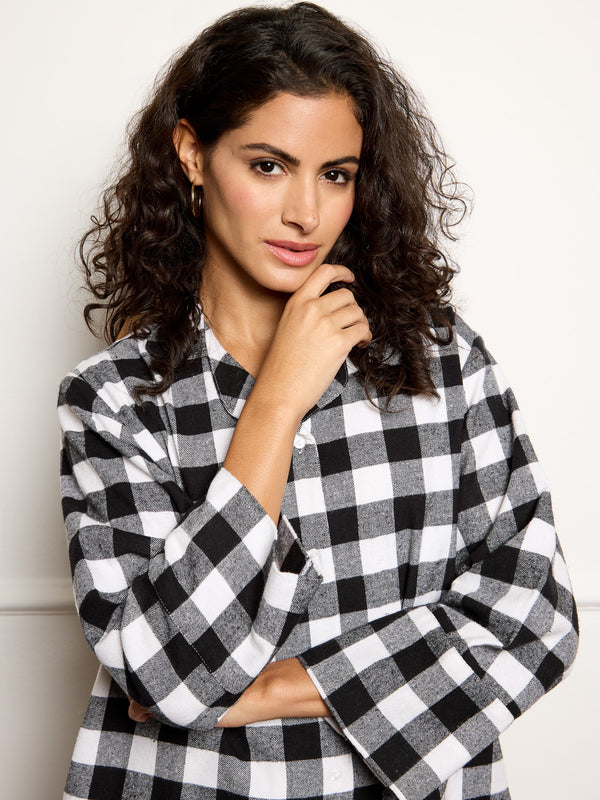 Woman wearing a black and white checkered pyjamas against a plain background