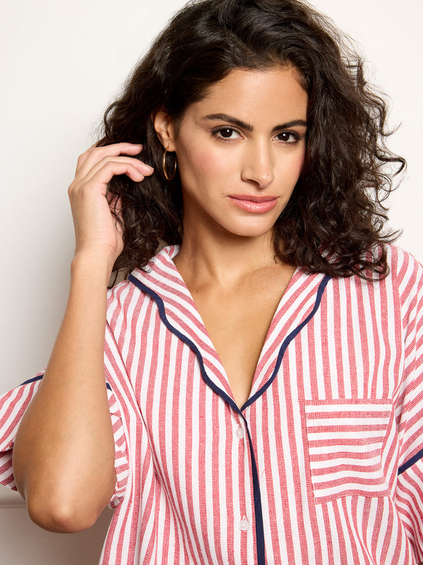 Woman wearing a red and white striped pajama top against a plain background