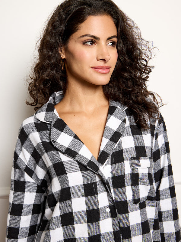Woman wearing a black and white checkered nightshirt against a plain background