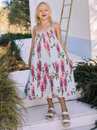 A child standing on a step wearing a floral night dress with double straps.