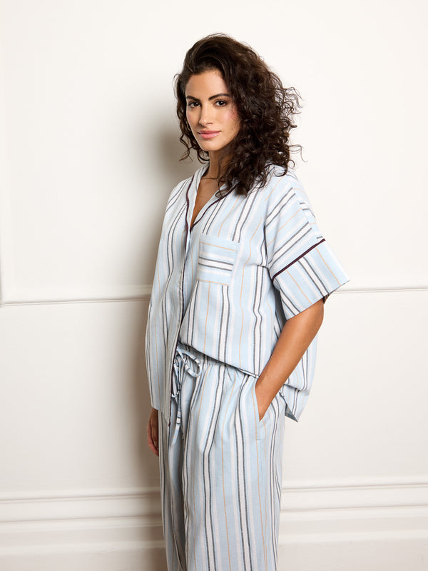 Woman wearing a light blue striped pyjamas against a white background