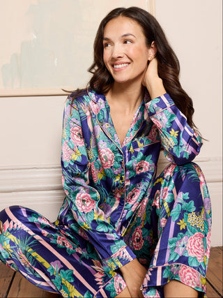 Woman wearing a colourful floral pyjama set sitting on a wooden floor.