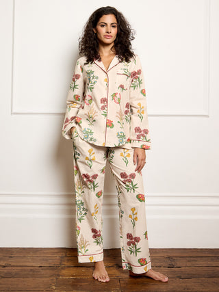Woman wearing a floral pyjama set against a white wall.