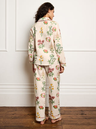 Person wearing a floral pyjama set against a white wall. Back Detail. 