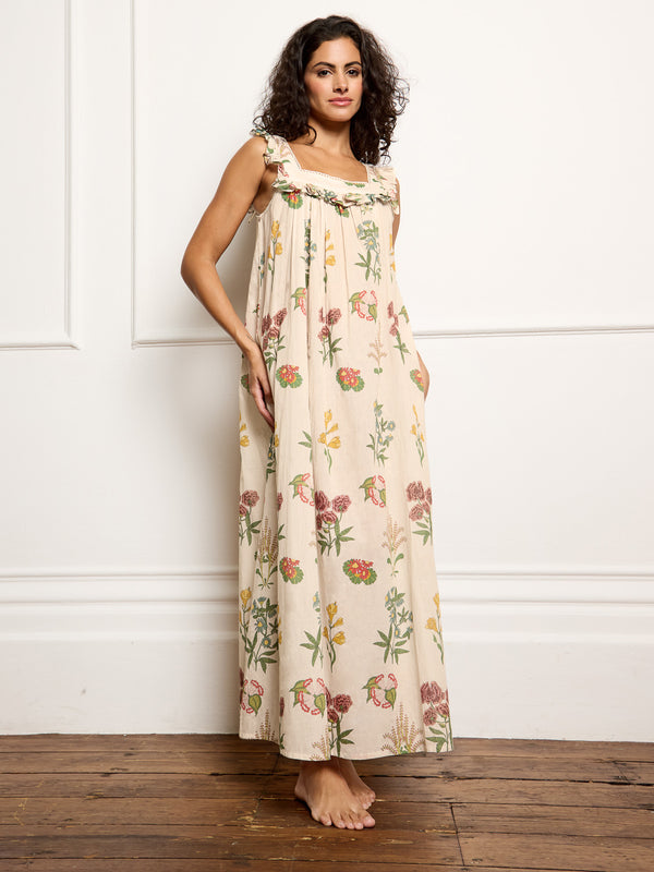 Woman wearing a floral night dress standing against a white wall.