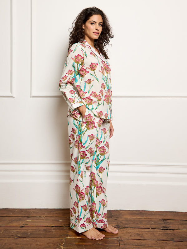 Model wears traditional long cotton pyjamas ion a hand drawn tulip print.