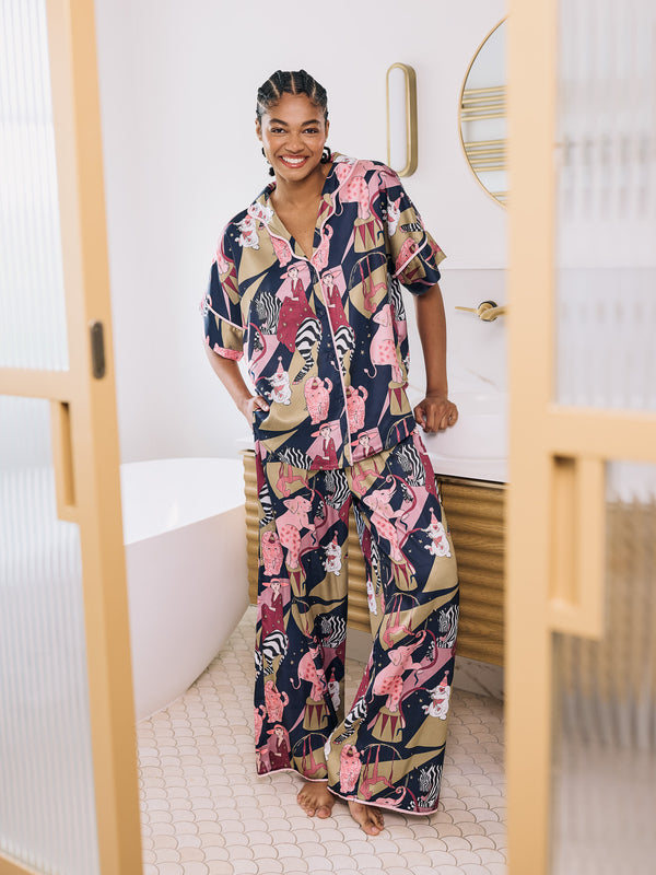 Woman wearing a colorful pajama set in a room with a white wall and wooden frame.