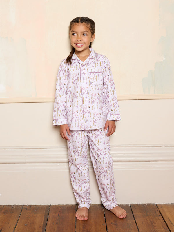 Young girl wearing a lilac floral pyjama set smiling against a plain background