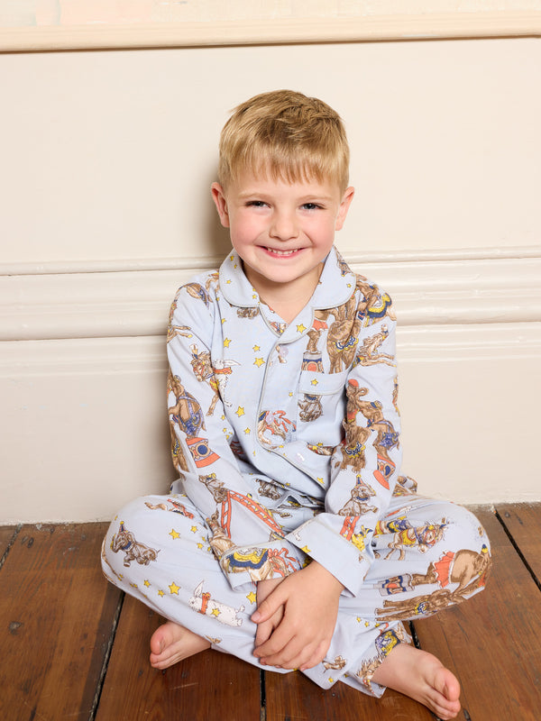 Little boy wearing blue cotton pyjama set with animal circus pattern sitting on the floor