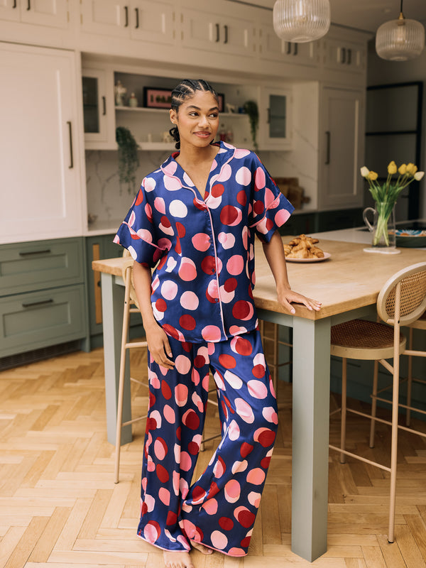 Woman in a polka dot pyjama set standing in a kitchen.