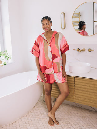  woman wearing abstract pink oversize satin pyjama short set in a bathroom