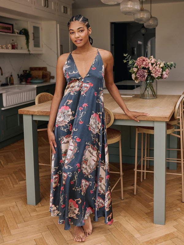 Woman in a gret floral night dress standing in a kitchen.