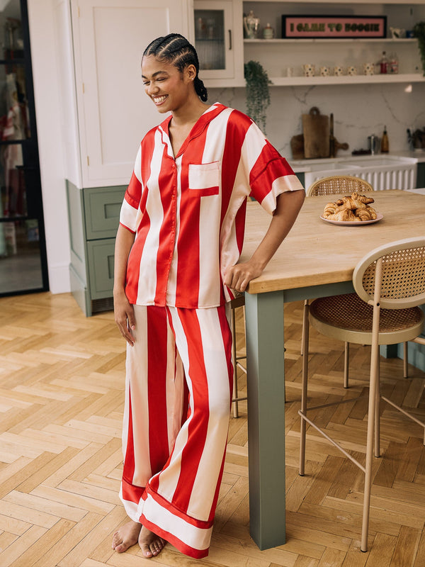 Woman in a red and white striped pyjama set standing in a kitchen.
