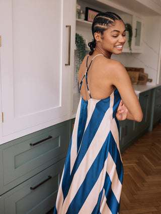 Woman in a blue and white striped dress standing in a kitchen.