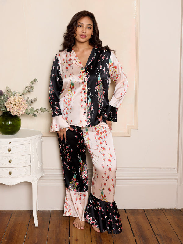 Woman wearing a floral pajama set in a room with a white dresser and flowers.