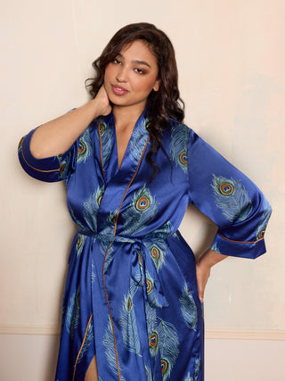 Woman wearing a blue satin robe with peacock feather pattern against a beige background
