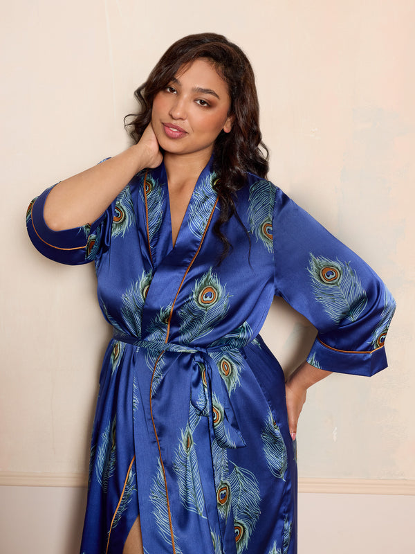 Woman wearing a blue satin robe with peacock feather pattern against a beige background