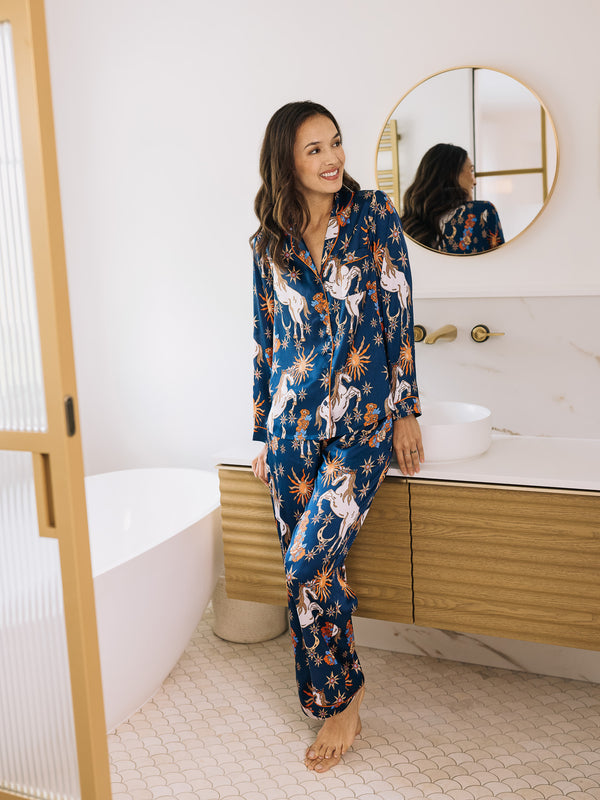 Woman wearing a blue unicorn patterned pajama set in a bathroom.