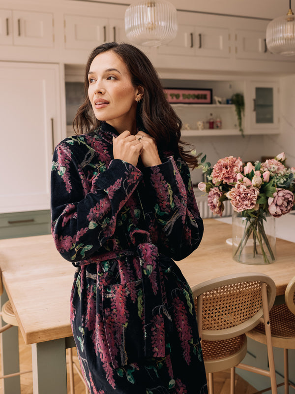 woman wearing black velvet robe with purple wisteria print feeling cosy