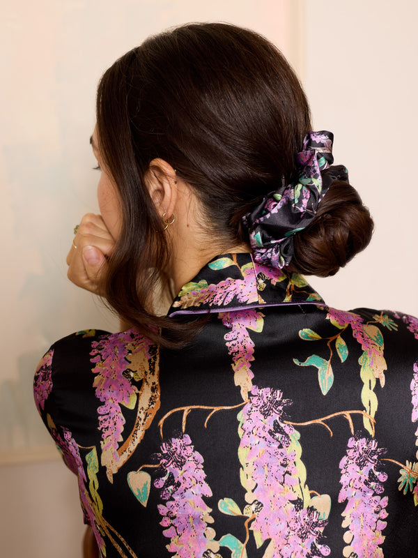 woman wearing black satin scrunchie with purple wisteria pattern in her hair