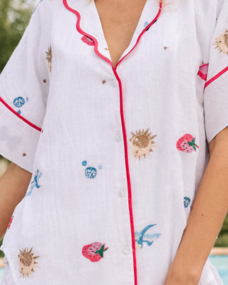White pajama top with colorful embroidery on a blurred outdoor background