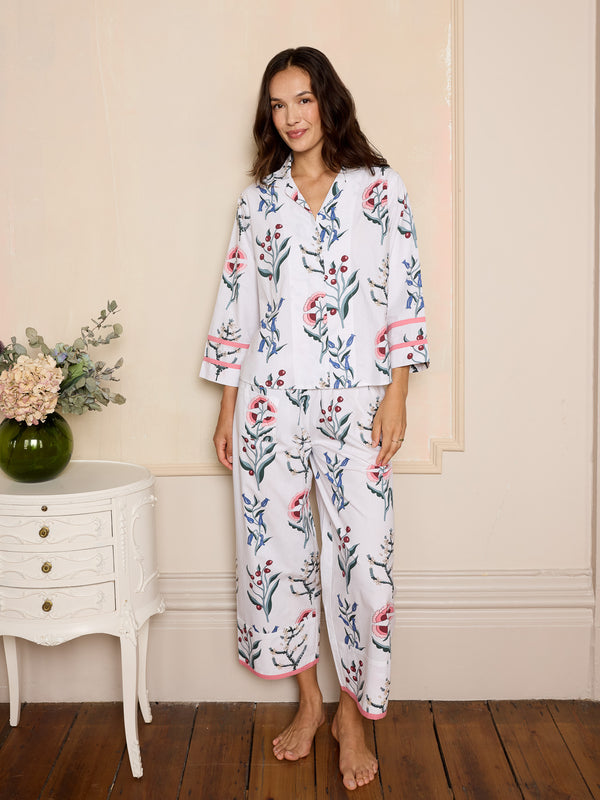 woman wearing white cropped cotton pyjamas with a floral design and pink details
