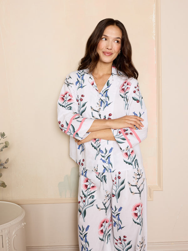 woman wearing white cropped cotton pyjamas with a floral design and pink details