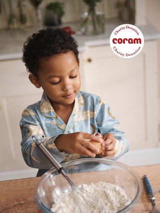 Child Model wears light blue cloudy sky pyjama while making pancakes