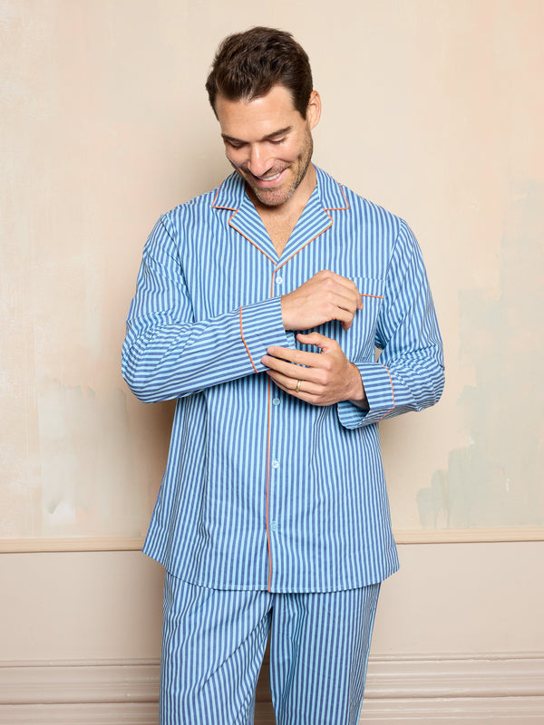 Man wearing a blue striped pajama set against a neutral background