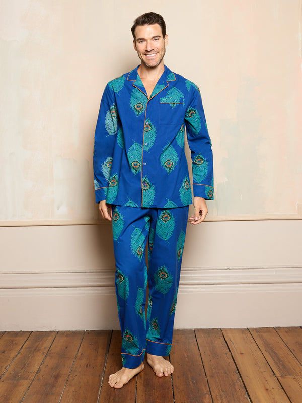man wearing blue cotton pyjamas with peacock feather pattern standing on wooden floor 