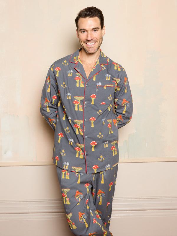 Man wearing a mushroom patterned pyjama set against a beige wall.