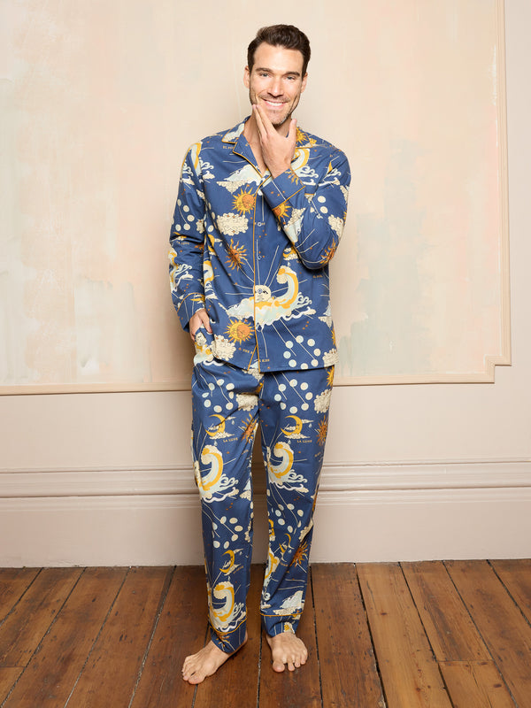 Man wearing a blue cotton pyjama set with celestial design standing in a neutral room