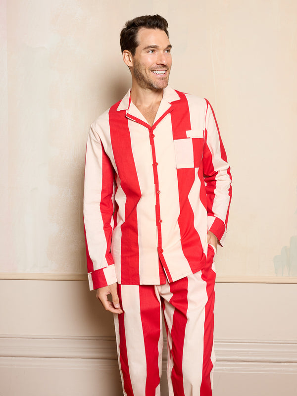 Man wearing red and white striped pyjamas against a beige wall.