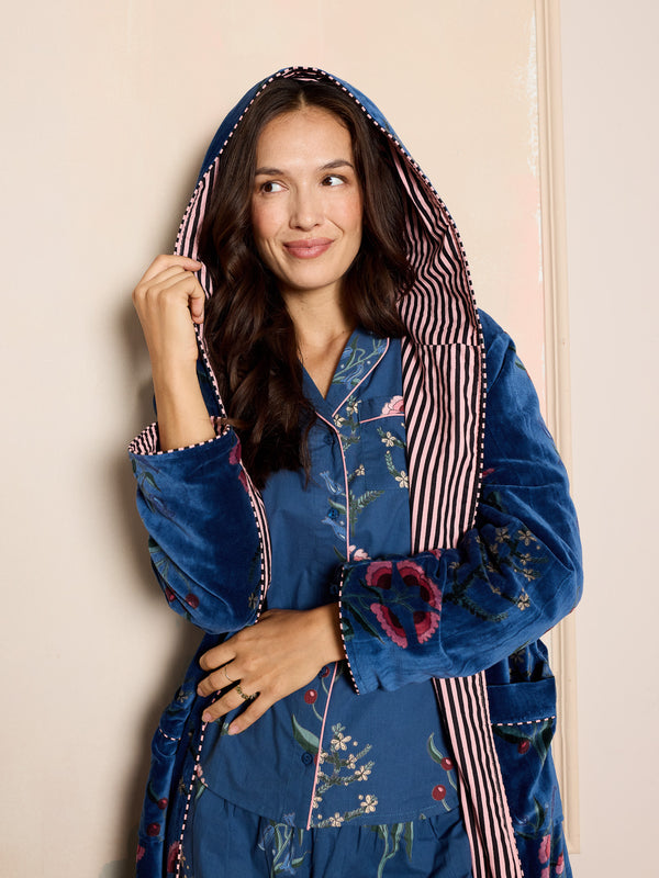 woman wearing navy velvet robe with floral pattern, wearing the hood up over her head