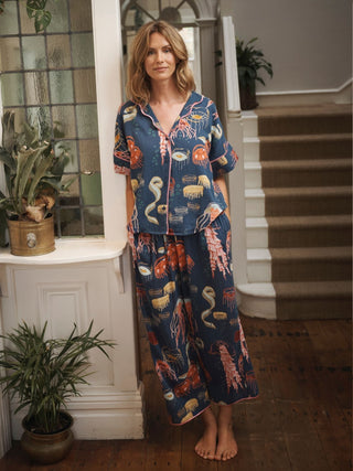 Model wears a pair of long pyjamas with ocean themed designs