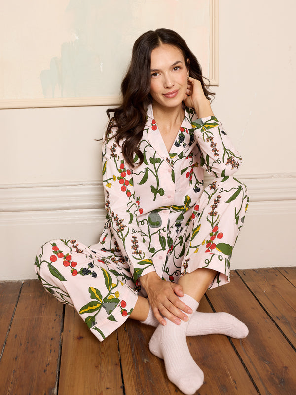 Woman wearing a floral pink pyjama set sitting on a wooden floor wearing cosy socks