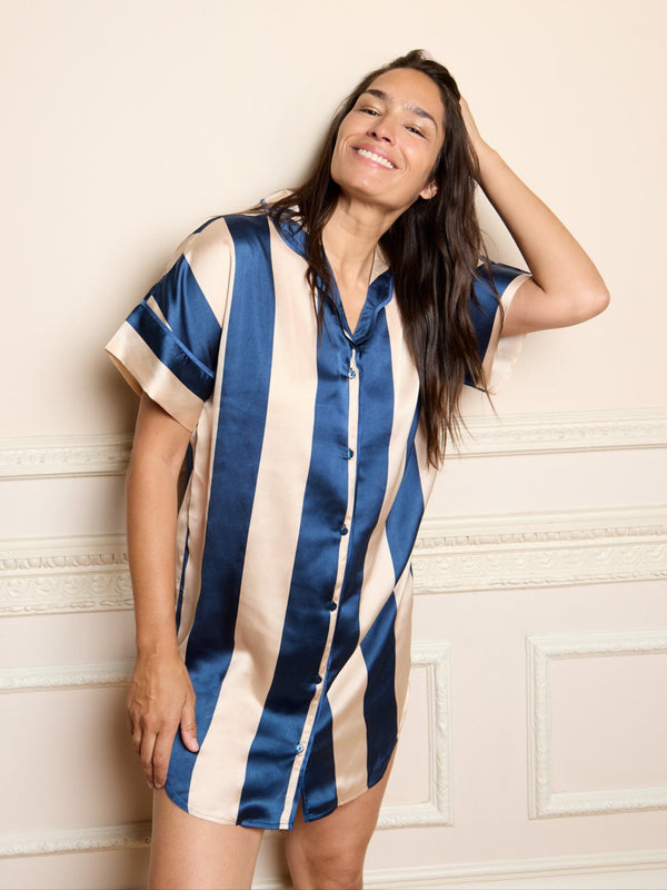 Woman wearing a blue and beige striped nightshirt against a beige wall