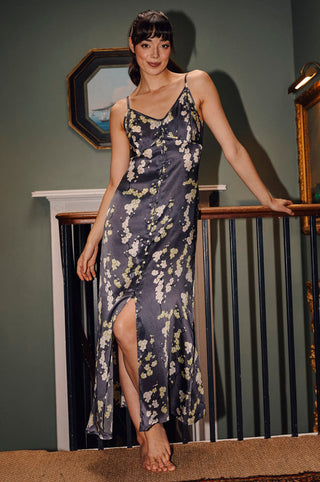 A woman standing on a staircase wearing a floral black and white cami nightie with spaghetti straps and lace trim.